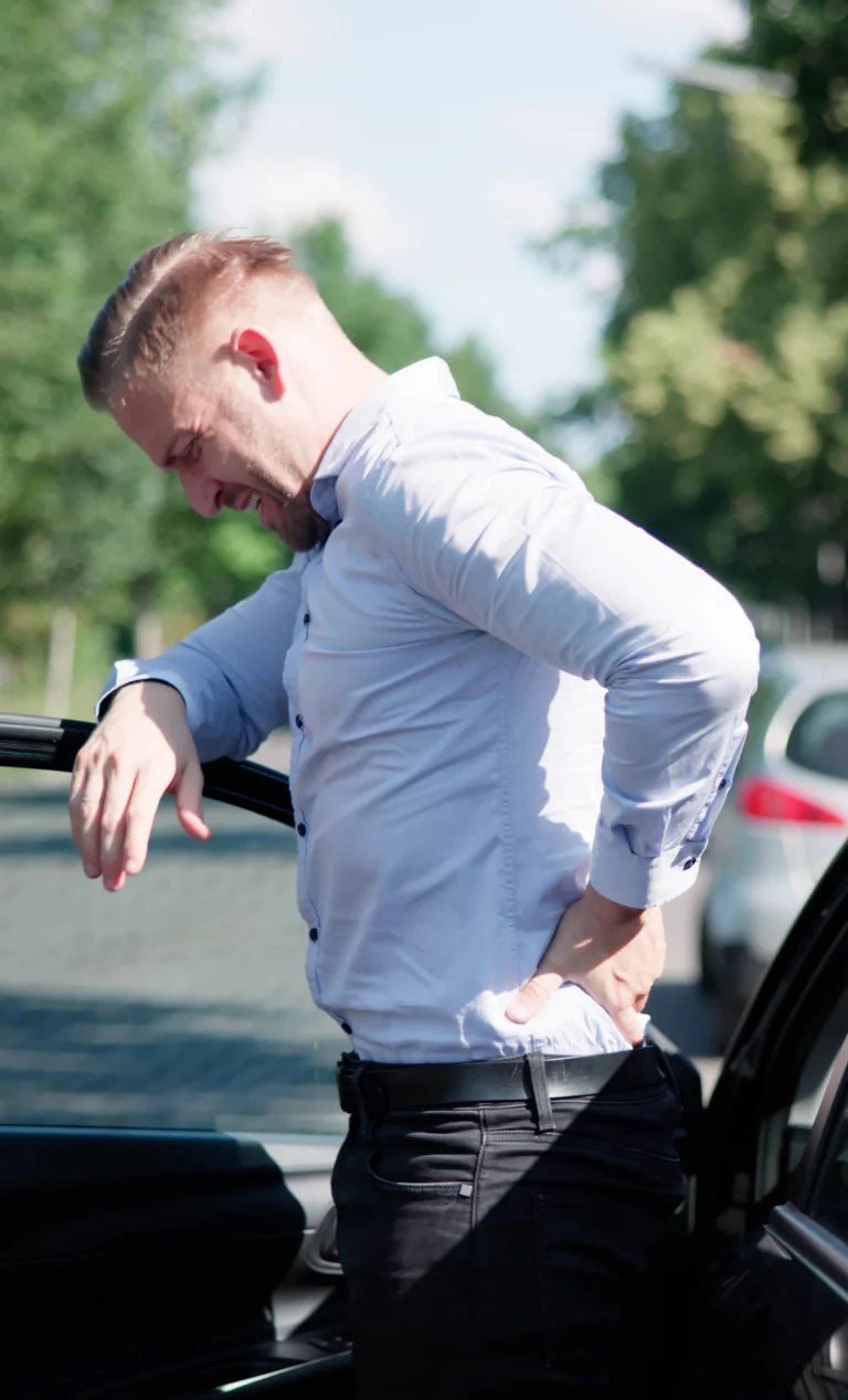 Man experiencing back pain after stepping out of a car