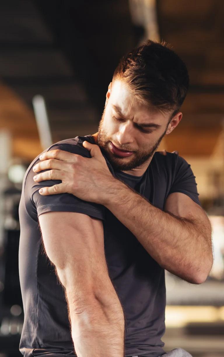 Man outdoors holding his shoulder in discomfort